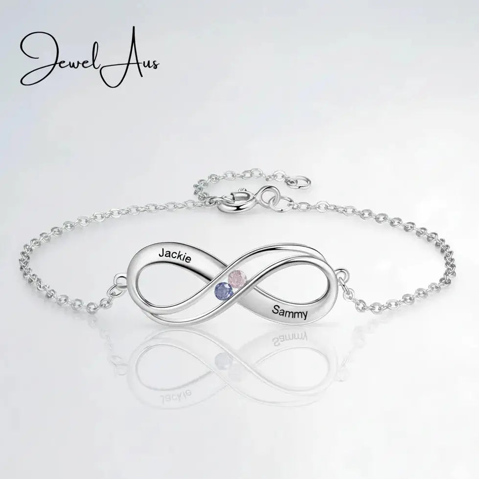 Silver infinity bracelet with engraved names on a light gray background, featuring the brand 'Jewel Aus'.