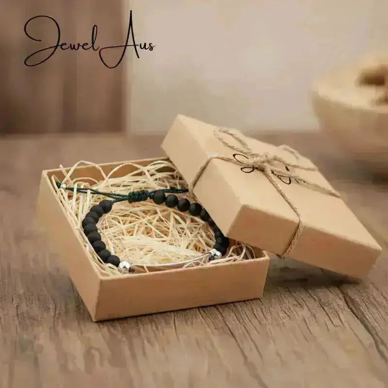 Bracelet in a brown gift box on a wooden surface with 'Jewel Aus' branding.