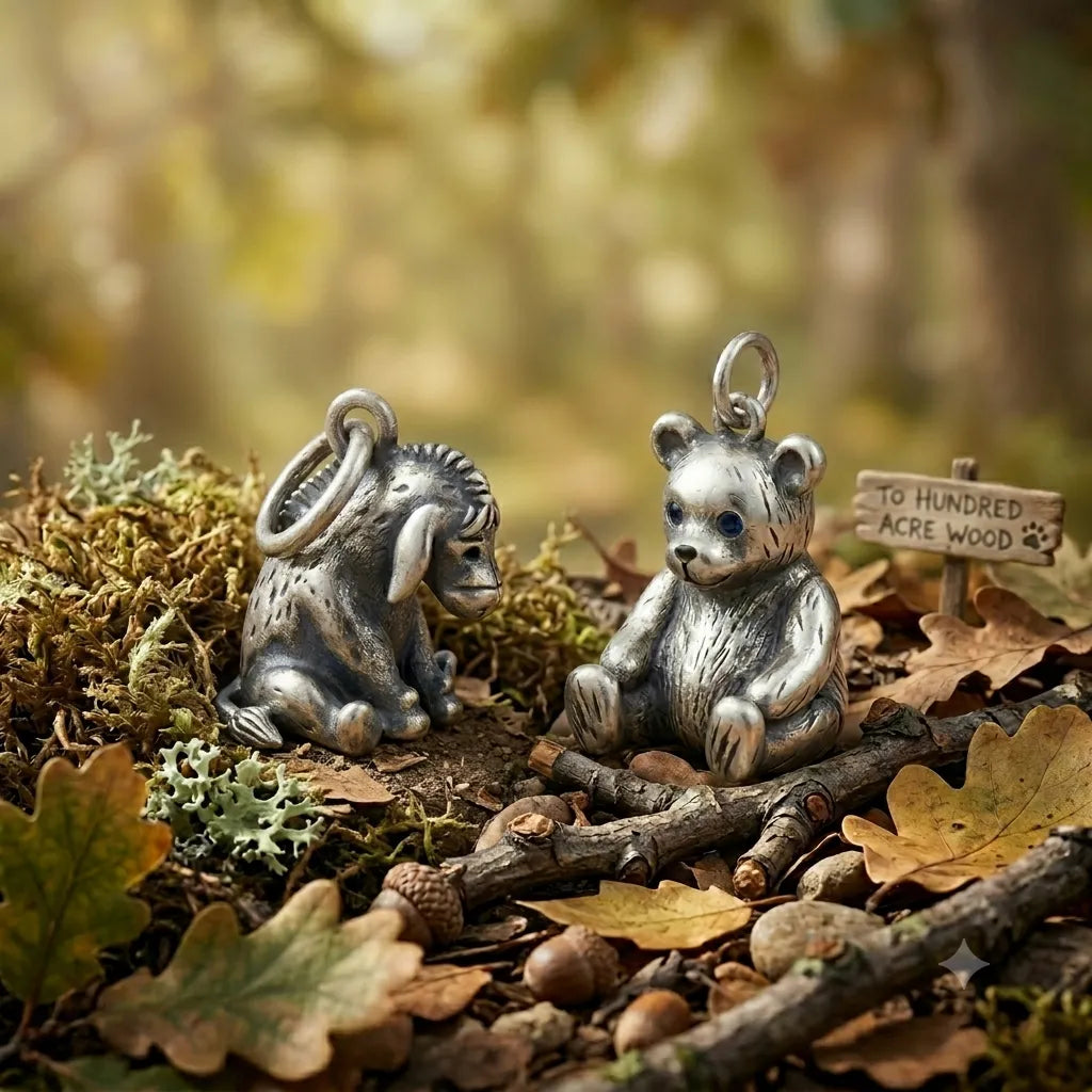 Two silver animal charms on a natural setting with leaves and twigs.