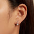 Close-up of a woman wearing a diamond earring with a neutral background