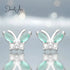 Butterfly-shaped earrings with green gemstones on a blurred background