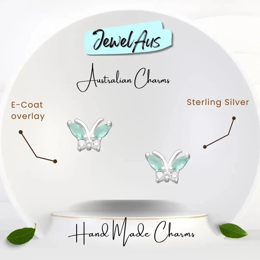 Butterfly-shaped charms on a white circular stand with 'Jewel Aus' branding.
