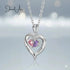 Heart-shaped silver necklace with two colored stones on a light gray background, featuring the brand 'Jewel Aux'.