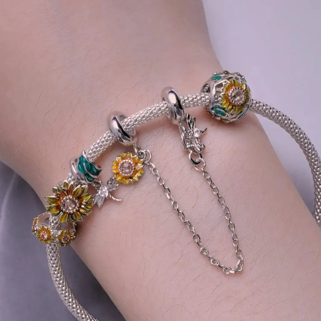 Silver bracelet with floral charms on a wrist against a neutral background